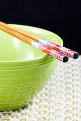 chopsticks on a ceramic bowl on black background