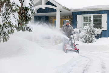 Obraz premium Man clearing driveway with snowblower
