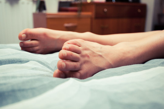 Feet of young woman on bed at home
