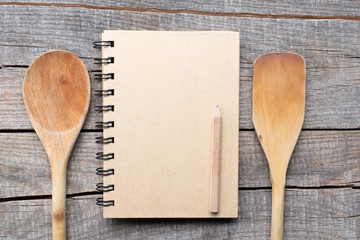 Old recipe notebook, spoons on wood background 