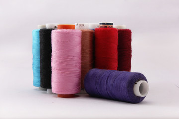 катушки ниток разного цвета на белом фоне