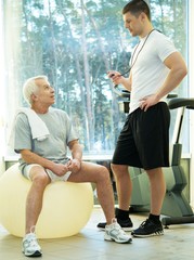 Trainer explains to a senior man how to do exercise 