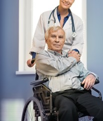 Fototapeta premium Cheerful young nurse woman with senior man in wheelchair