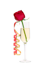 Red rose in glass of champagne and paper streamer.