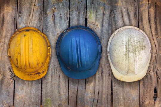 Three vintage construction helmets on a wooden wall