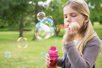 Girl blowing soap bubbles at park