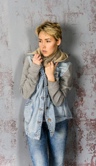 girl with short hair wearing jeans and a jacket at the wall