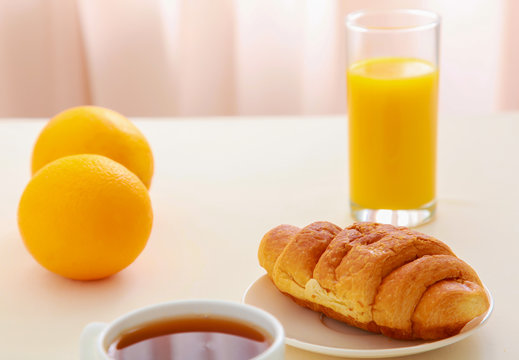 Croissants, Coffee, Orange Juice and Newspapers on table.