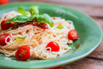 Spaghetti with tomatoes and basil on wooden background