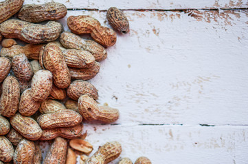 Fototapeta premium Roasted peanuts on white wooden background