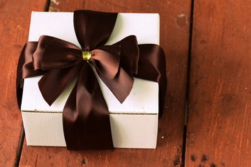 white gift box with ribbon bow on a wooden background