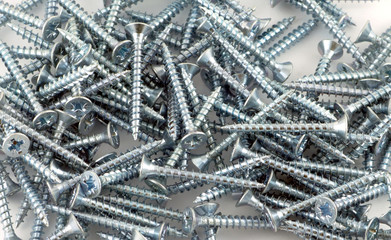 Heap of gray screws on white background closeup