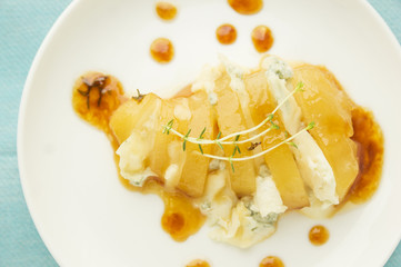 Baked Caramelized pear with gorgonzola,thyme in plate on blue