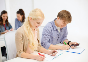 Fototapeta premium smiling students with notebooks at school