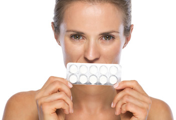 Woman holding blistering package of pills in front of mouth