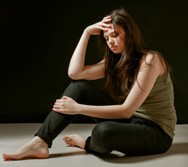 Depressed woman sitting on floor with eyes closed.