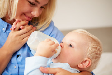 Mother Giving Baby Son Bottle Of Milk