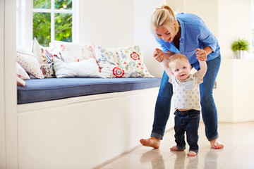 Fototapeta premium Mother Helping Young Son As He Learns To Walk