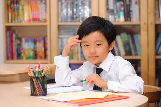 Schoolboy wearing white shirt and tie sitting at a desk