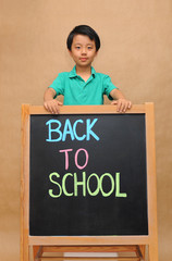 Boy standing above a blackboard with Back To School inscription