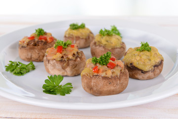 Stuffed mushrooms on plate on table on light background