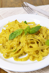 Delicious pasta with pesto on plate on table close-up