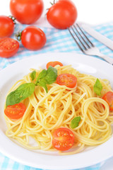 Delicious spaghetti with tomatoes on plate on table close-up