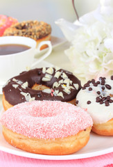 Sweet donuts with cup of tea on table on light background