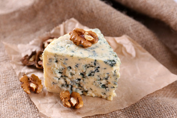 Tasty blue cheese with nuts, on burlap background
