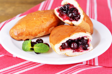 Fresh baked pasties with currant on plate on table close-up