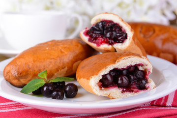 Fresh baked pasties with currant on plate on table close-up