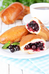 Fresh baked pasties with currant on plate on table close-up