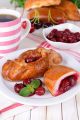 Fresh baked pasties with cherry on plate on table close-up