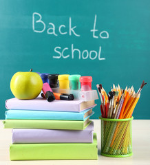 School supplies on table on blackboard background