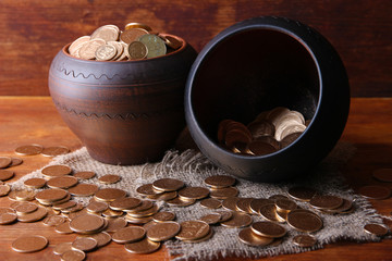 Golden coins in ceramic pots, on wooden background
