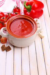 Tasty tomato soup and vegetables on wooden table