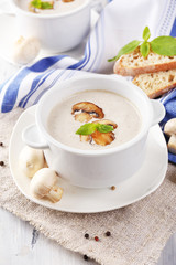 Mushroom soup in white pots, on napkin,  on wooden background
