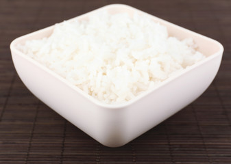 Cooked rice in bowl on bamboo background