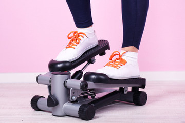 Woman doing exercise on stepper. Close-up on legs.