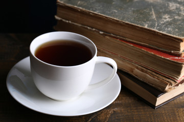 Cup of hot tea with books on table close up