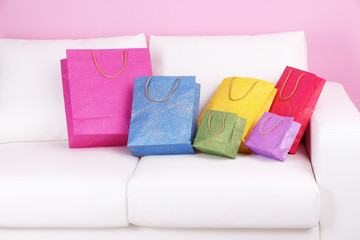 Colorful shopping bags on sofa, on color wall background