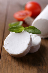 Tasty bushe cheese with basil and tomato, on wooden table