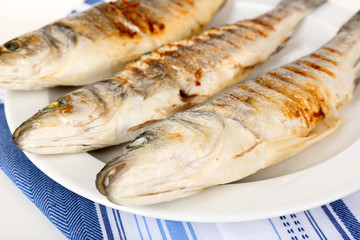 Delicious grilled fish on plate on table close-up