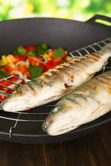 Delicious grilled fish on wok close-up