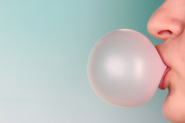 Person doing bubble with chewing gum on bright background