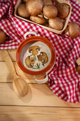 Mushroom soup in pot, on napkin,  on wooden background