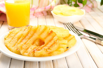 Juicy grilled pineapple on plate on table close-up