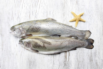 Two rainbow trouts and starfish on rustic wooden table