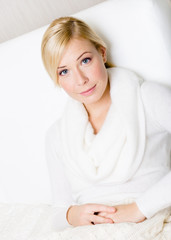 Portrait of pretty blond woman sitting on the white sofa