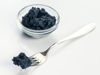 Fototapeta na wymiar Metallic fork with black caviar on white background